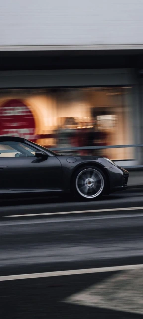 Black Porsche Driving Past Storefront