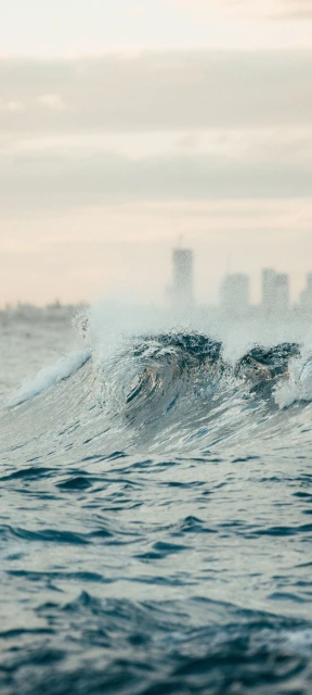 Ocean Wave Breaking With City Skyline Background